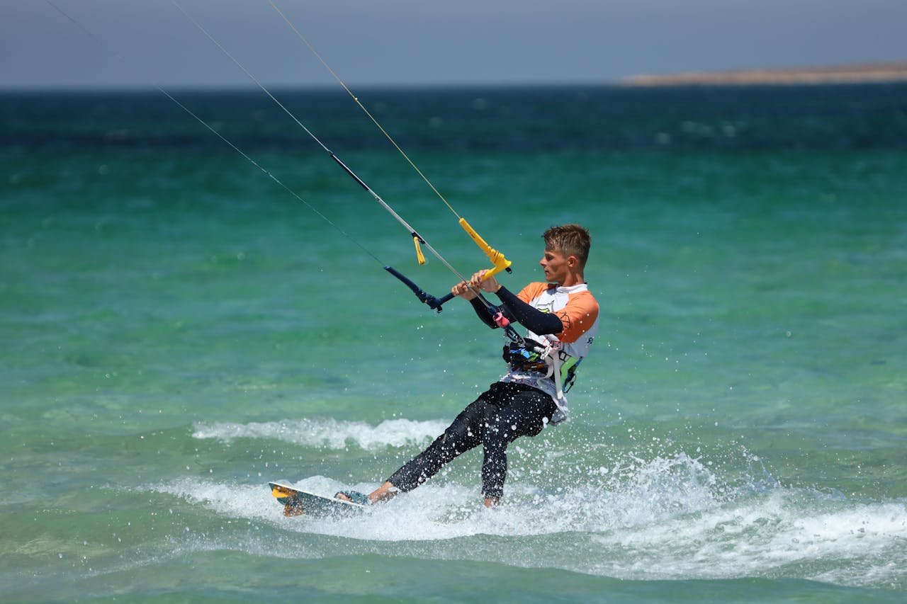 Man kiteboarding on the ocean, showcasing vibrant water sports and adventure.