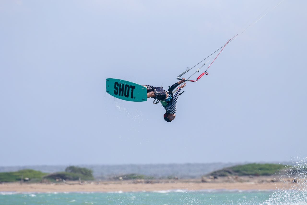 Action-packed kitesurfing captured mid-air against a scenic ocean backdrop.