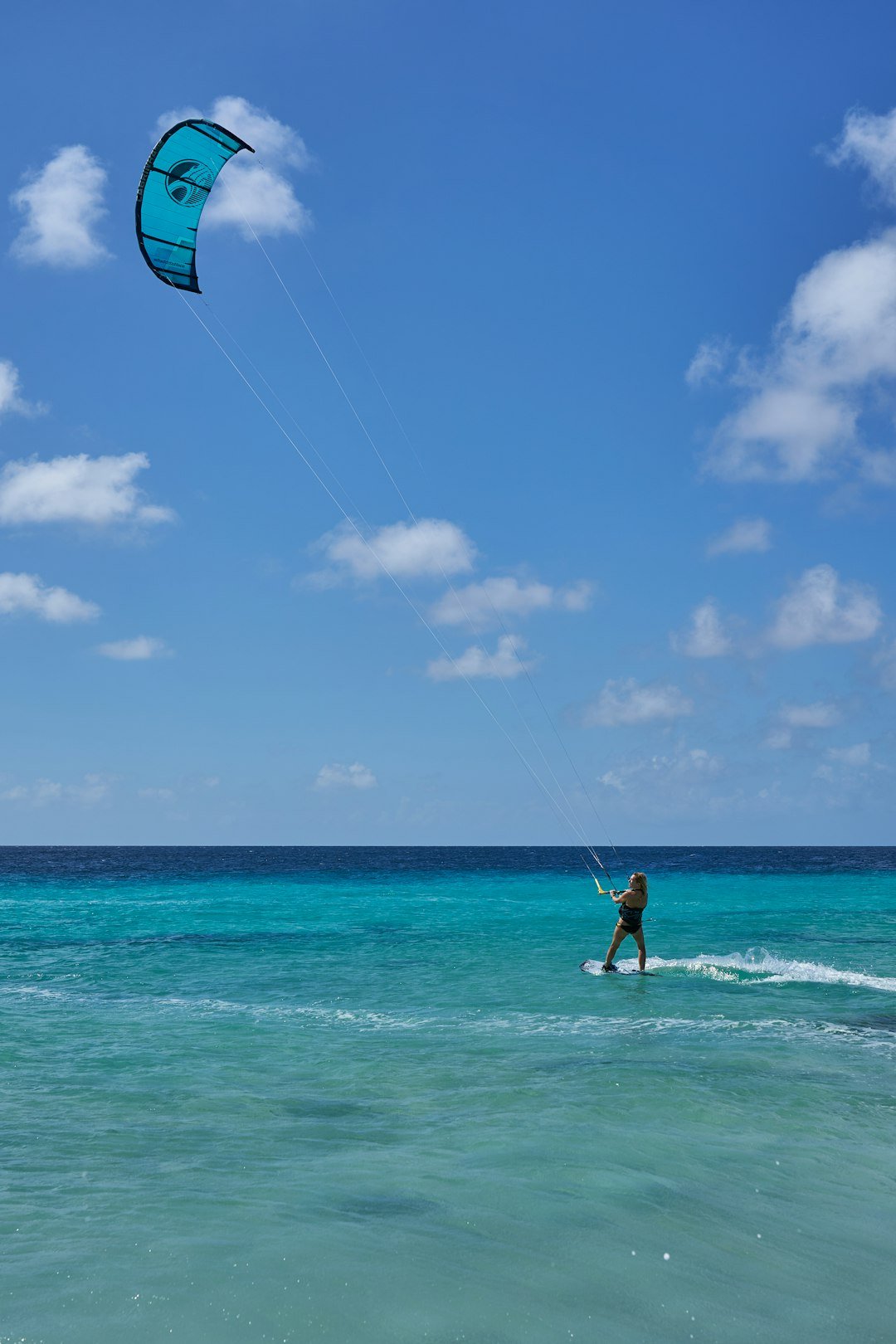 woman-in-white-and-black-bikini-holding-blue-and-white-kite-surfing-on-sea-during-daytime-sy8-wqti5wg